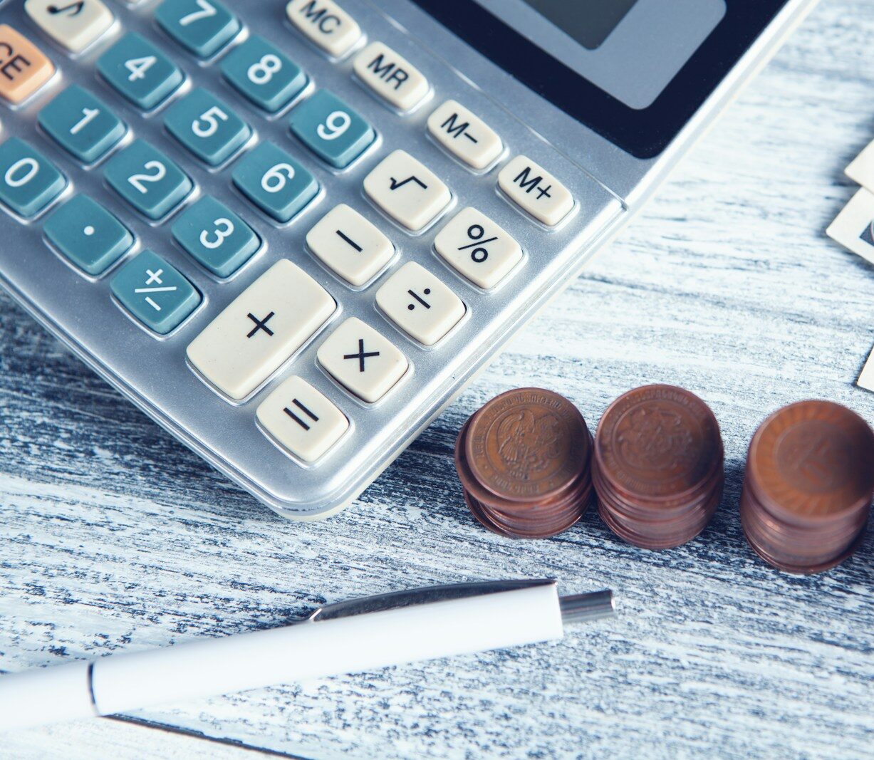 a calculator, pen, and money on a table